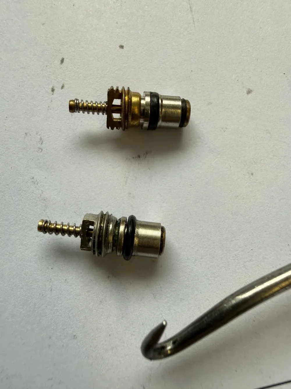 Old worn AC valve stem next to a new replacement at Beacon Auto Care San Mateo
