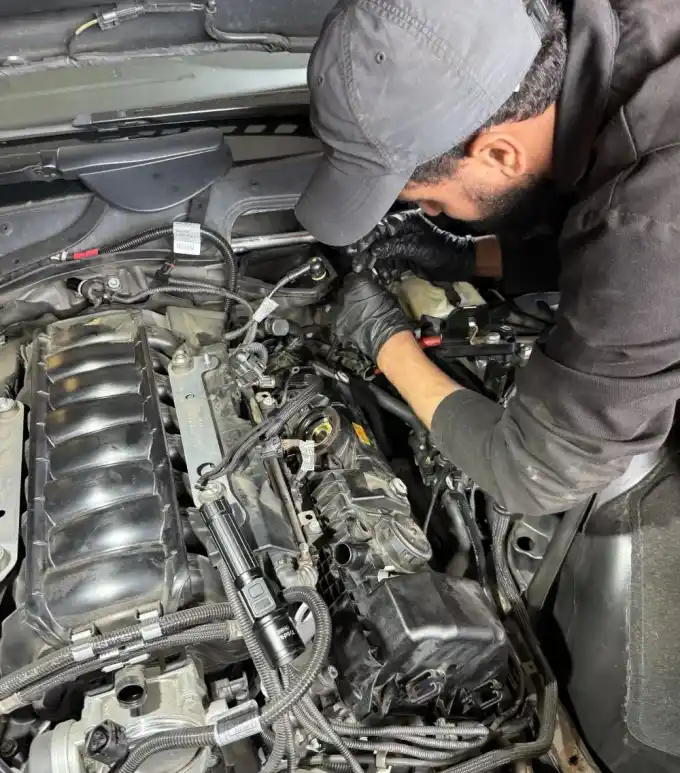 Favio, lead mechanic at Beacon Auto Care San Mateo, working on a 2006 BMW 550i N62 V8 engine bay during a valve cover replacement