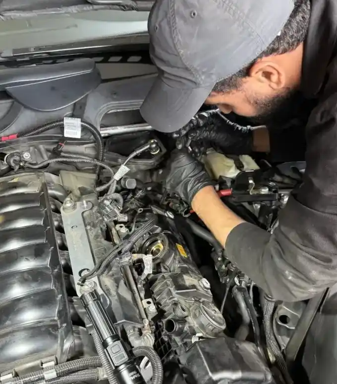 Favio, lead mechanic at Beacon Auto Care San Mateo, working on a 2006 BMW 550i N62 V8 engine bay during a valve cover replacement