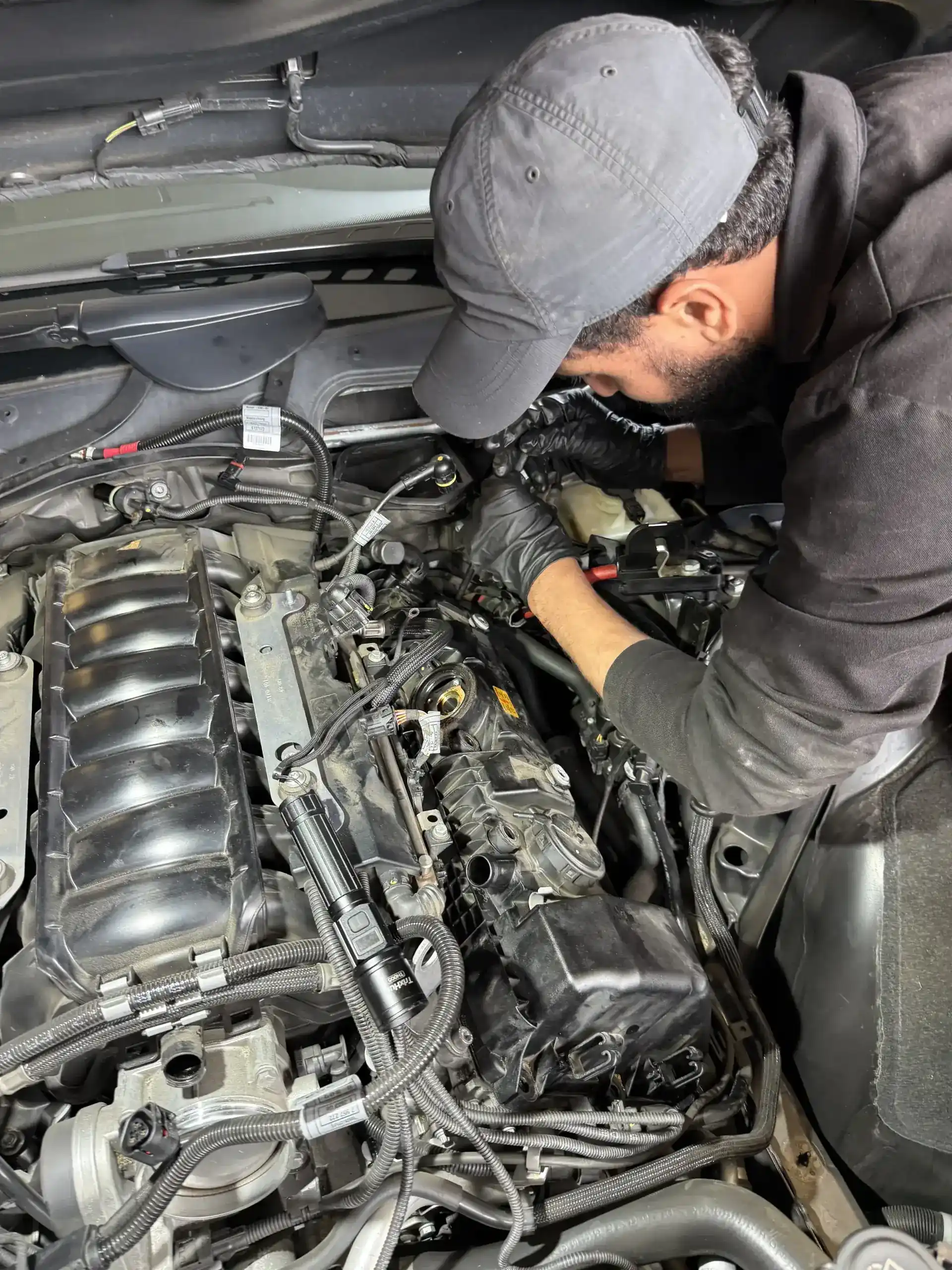 Beacon Auto Care technician working on a BMW inline-6 valve cover removal at the San Mateo shop