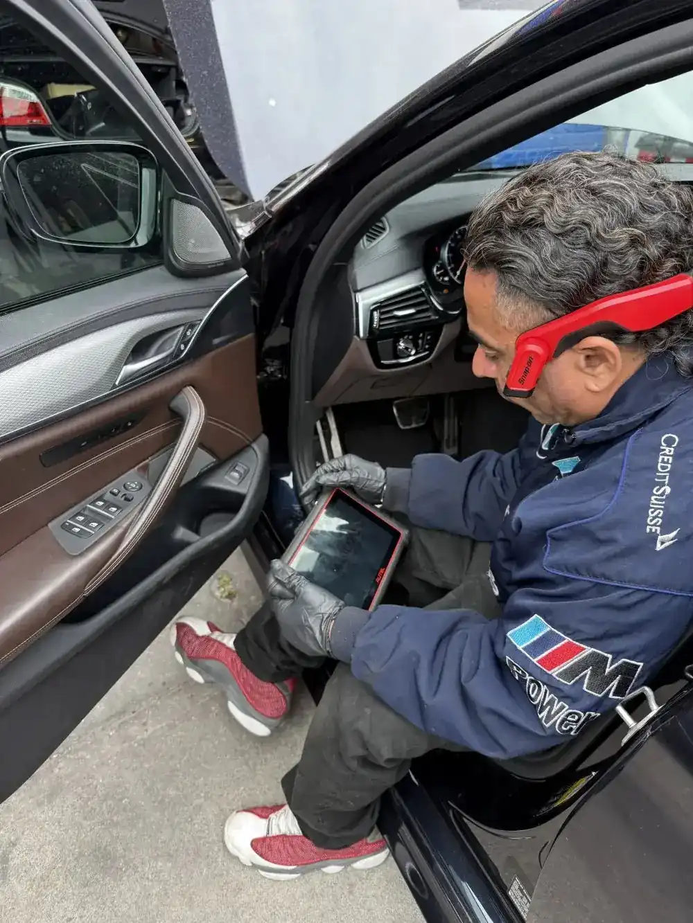 Favio, lead mechanic at Beacon Auto Care San Mateo, in the driver door of a BMW M550i (G30 N63 V8) running an Autel diagnostic scan mid-pull