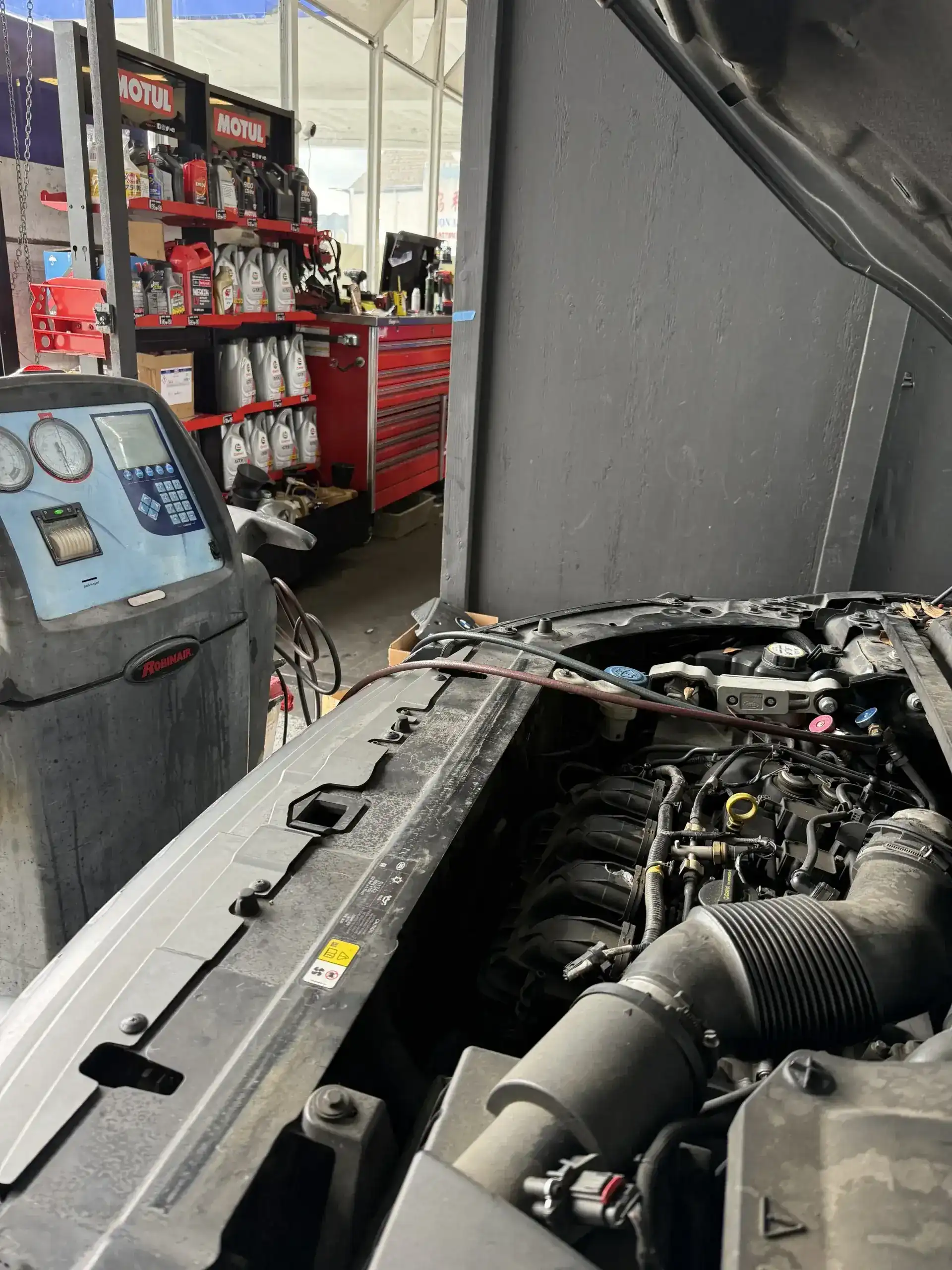 Ford engine bay AC service with Robinair recharge machine connected at Beacon Auto Care San Mateo