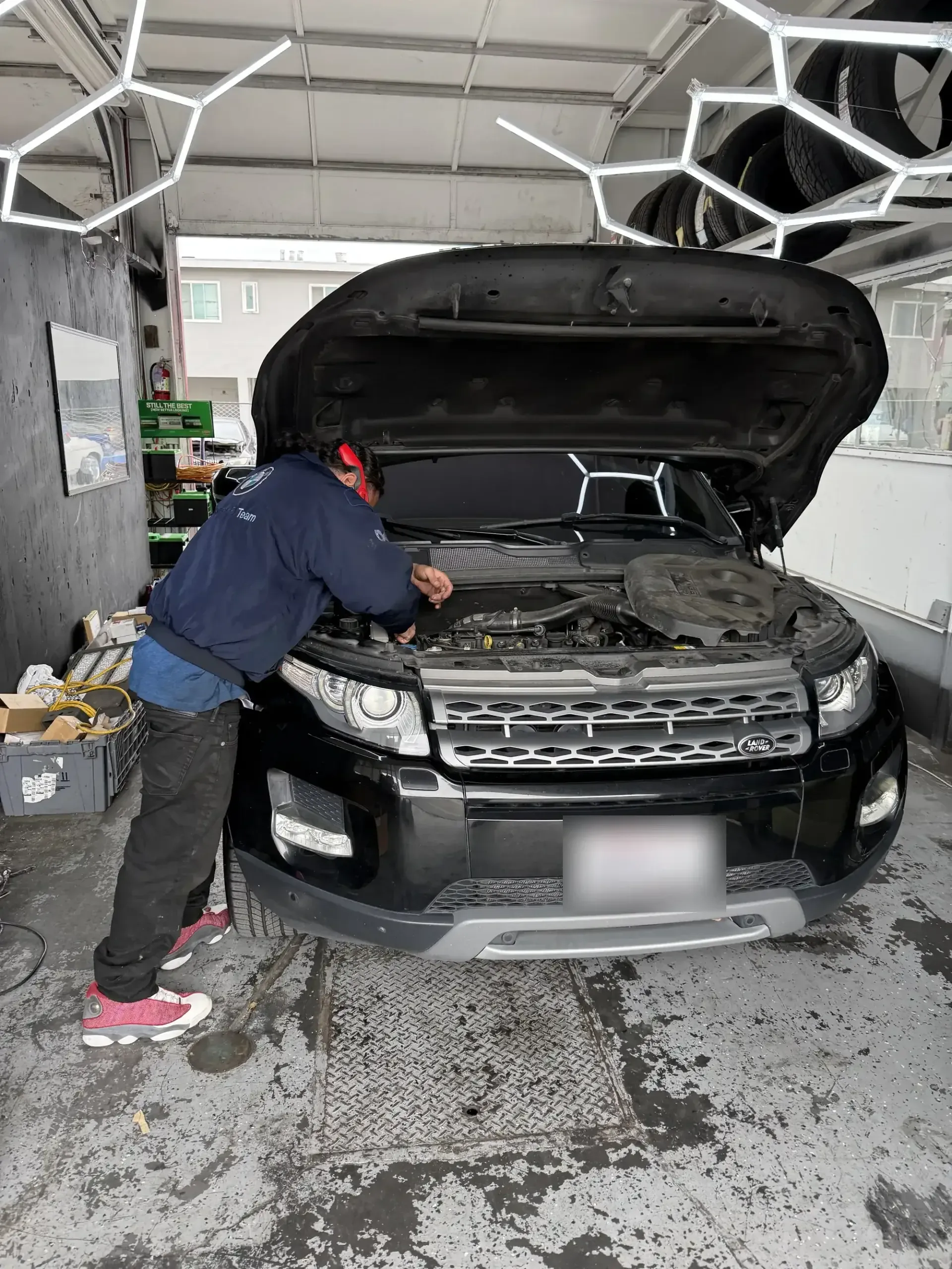 Favio, lead mechanic at Beacon Auto Care San Mateo, leaning into the engine bay of a Range Rover Evoque diagnosing a fault