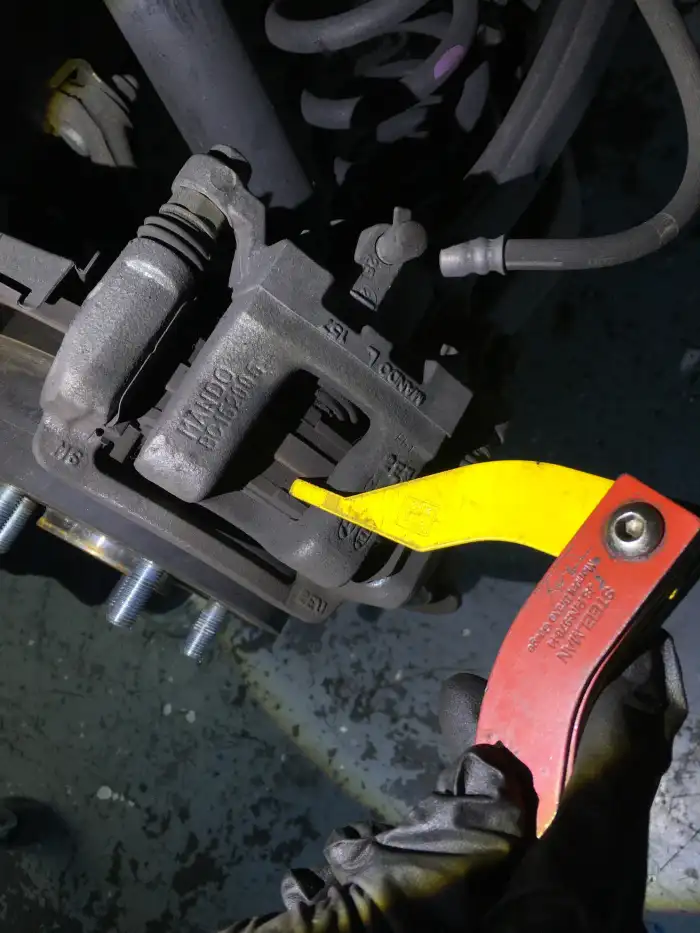 Technician checking a brake caliper with a gauge on a 2013 Hyundai Sonata — the front calipers were hard to retract during the inspection