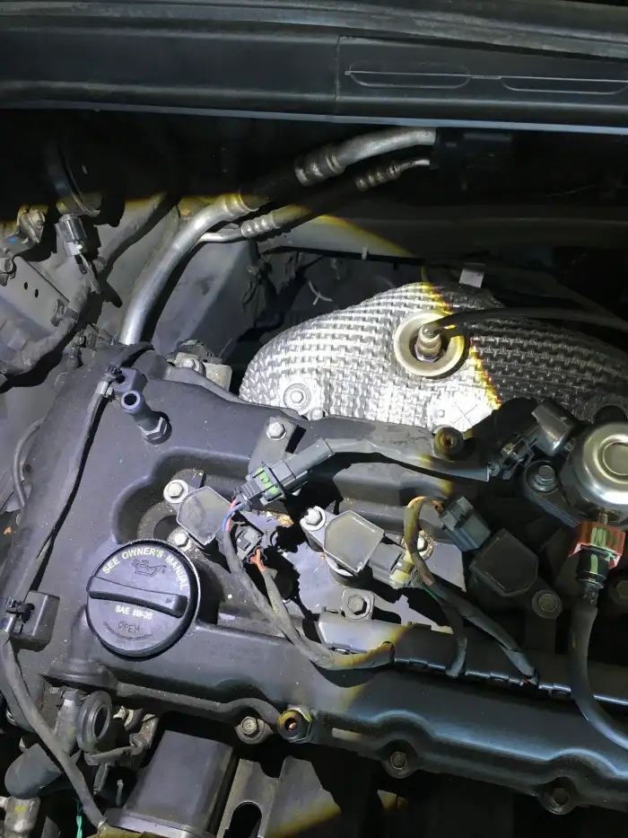 Engine oil leaking around the valve cover gasket of a 2013 Hyundai Sonata, photographed during a San Mateo vehicle inspection