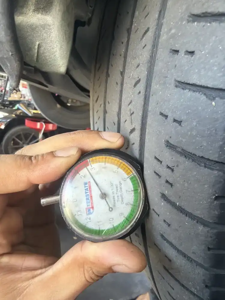 Tire tread depth gauge showing 2/32 inch reading on a worn tire — Beacon Auto Care San Mateo digital inspection