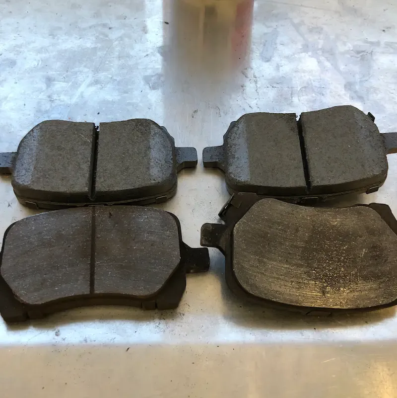 Worn brake pads next to new brake pads showing material loss — example DVI finding at Beacon Auto Care San Mateo